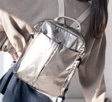 Silver backpack with a neutral background