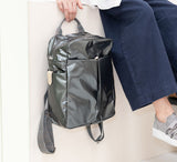 Person holding a metallic backpack on a light background