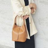 Person holding a tan handbag against a light gray background