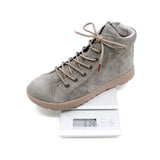 A gray suede high-top sneaker with beige laces and a beige sole, shown resting on a white digital scale against a white background.