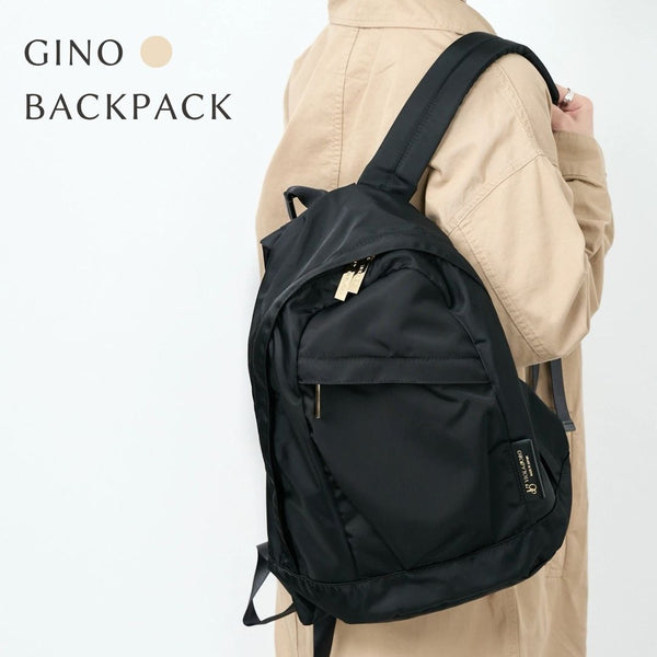 GINO Black backpack worn by a person in a beige coat on a white background