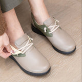 Person putting on a pair of Soune Grege Sneakers with green accents on a wooden floor.