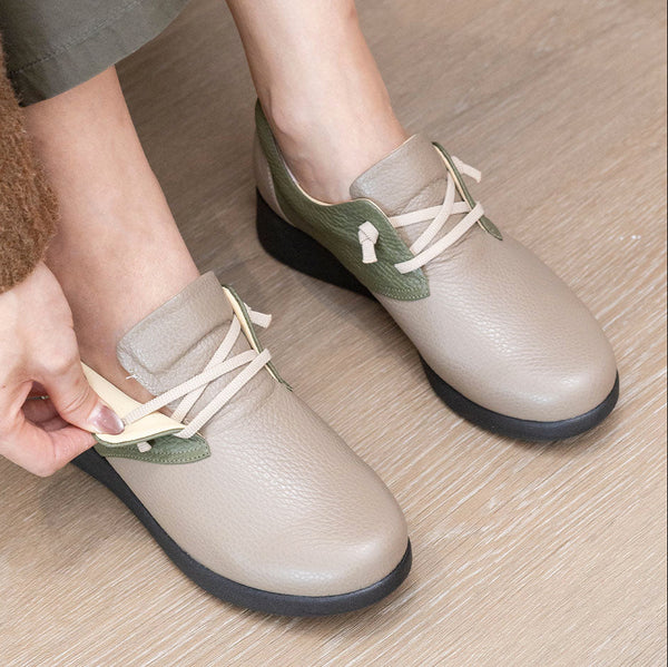 Person putting on a pair of Soune Grege Sneakers with green accents on a wooden floor.