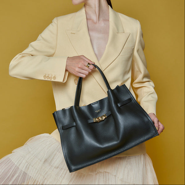 Woman holding a black handbag against a yellow background
